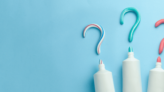 Colorful toothpaste swirls shaped like question marks alongside toothpaste tubes on a blue background.
